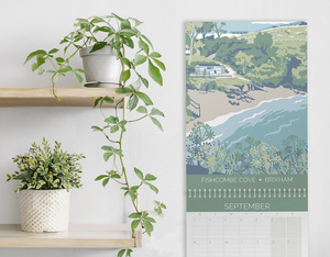 hillfolk calendar on wall next to shelf with plant. Calendar features view of Fishcombe for the month of September
