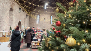 View inside the Spanish Barn with christmas tree in the foreground and people browsing craft stalls